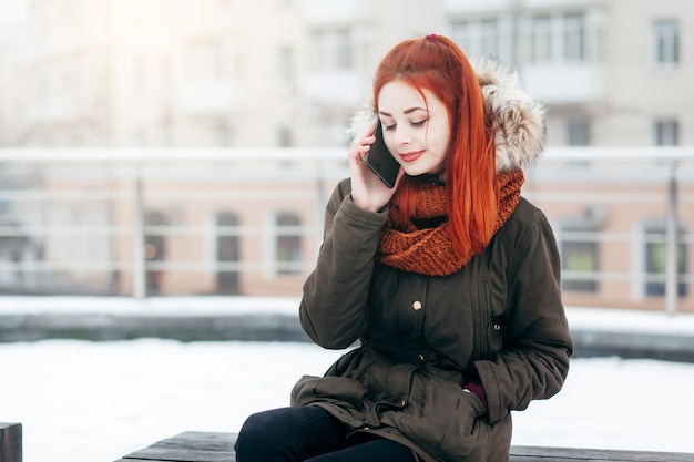 Mulher feliz ligando para o celular na rua no inverno