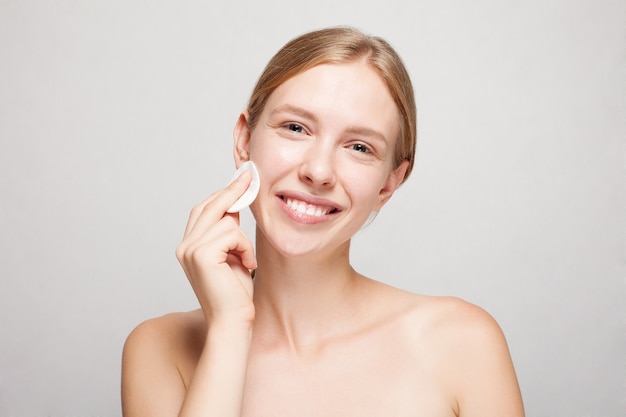 Mulher feliz limpando o rosto com almofadas de algodão