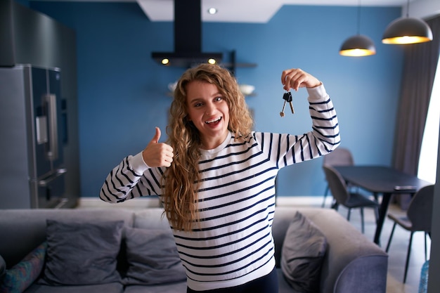 Foto mulher feliz mostrando novas chaves de casa ou apartamento para a câmera no interior moderno inquilino inquilino feminino com novas chaves de casa, movendo-se para locação senhora comprou imóveis, realocando conceito de propriedade