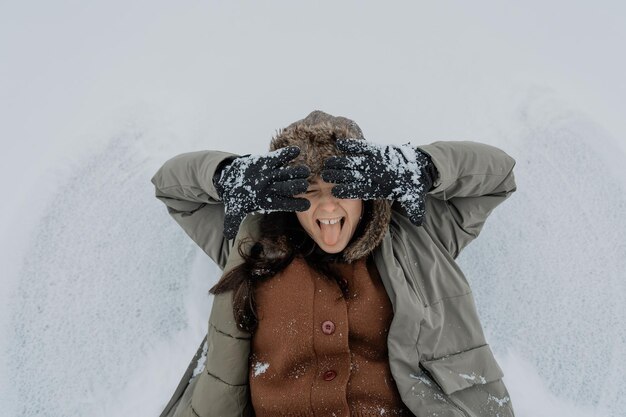 Mulher feliz na floresta de inverno desfrutando da primeira neve Uma jovem mulher com um chapéu está se divertindo na natureza de inverno Estilo de vida