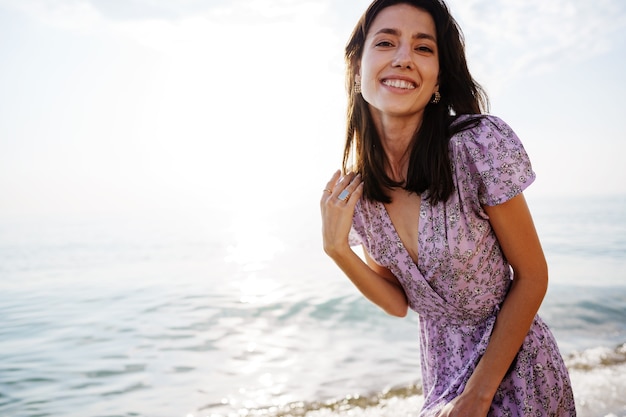 Mulher feliz na praia caminhando à beira-mar