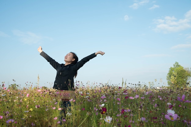 Mulher feliz no campo de beleza com flores cosmos