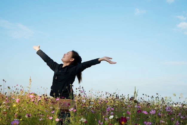 Mulher feliz no campo de beleza com flores cosmos