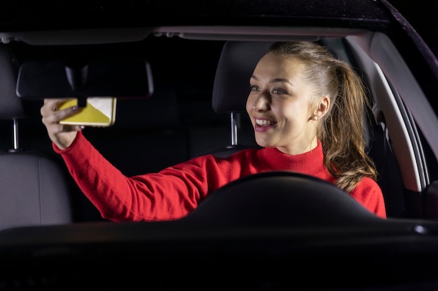 Mulher feliz no carro à noite parou de estacionar e fez videochamadas para a família