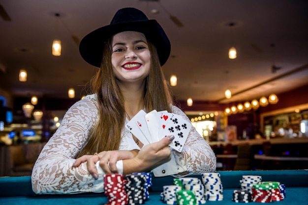 Mulher feliz no cassino com fichas e cartas de pôquer