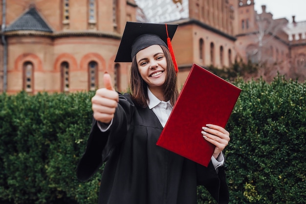 Mulher feliz no dia da formatura, universidade. educação e pessoas. certo sinal.