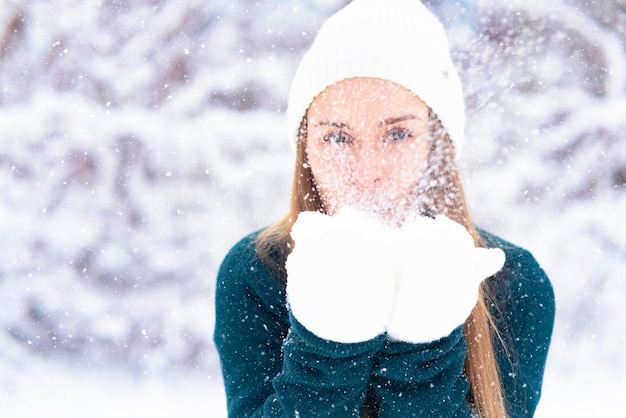 Mulher feliz no fundo da floresta, a neve cai sobre a garota, a fêmea sorri no inverno.