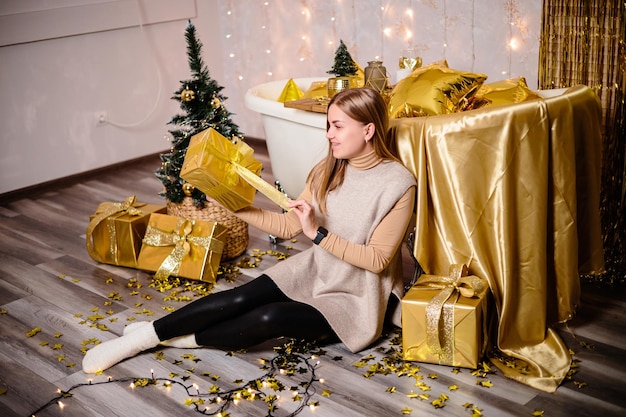 Mulher feliz no quarto de ano novo decoração de ano novo do quarto na cor dourada o conceito de férias e design festivo decoração de casa para o ano novo