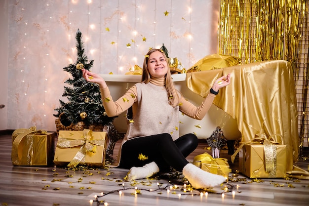 Mulher feliz no quarto de ano novo Decoração de ano novo do quarto na cor dourada O conceito de férias e design festivo Decoração de casa para o ano novo