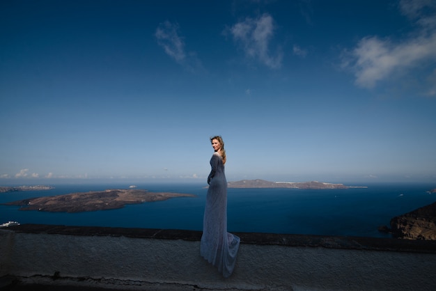 Mulher feliz no vestido branco e chapéu de palha, aproveitando suas férias na ilha de Santorini. Vista no mar Egeu de Oia. Destino de viagem de verão na Europa. Ilhas gregas
