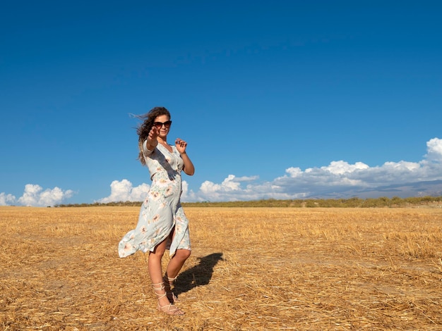 Mulher feliz no vestido esticando o braço para a câmera em campo