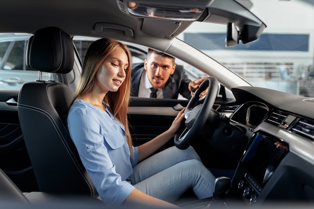 Mulher feliz, nova proprietária de carro, sentada no banco do motorista e olhando ao redor