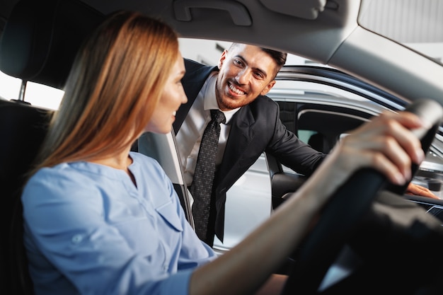 Mulher feliz, nova proprietária de carro, sentada no banco do motorista