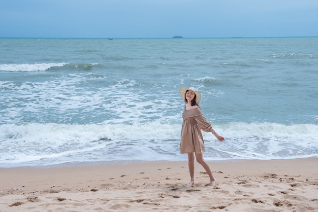 Mulher feliz nova que anda na praia com apreciação e feliz