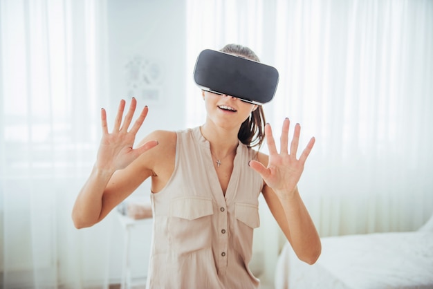 Mulher feliz obtém experiência com o uso de headset de realidade virtual de óculos VR em um ambiente brilhante