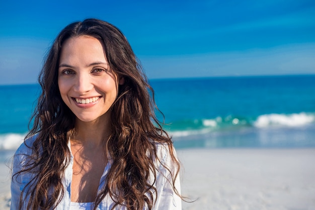 Mulher feliz olhando a câmera na praia