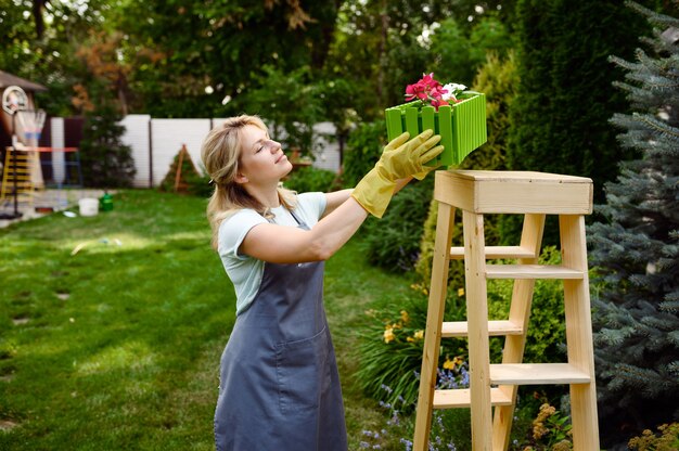 Mulher feliz olhando para um canteiro de flores no jardim