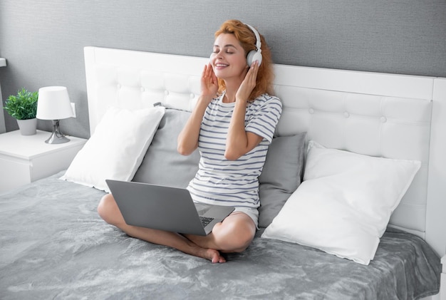 Mulher feliz ouve música em fones de ouvido mulher ouve música em casa usando fones de ouvido