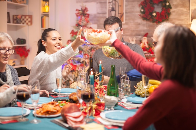 Mulher feliz, passando a salada sobre a mesa para a filha no jantar de Natal em família.