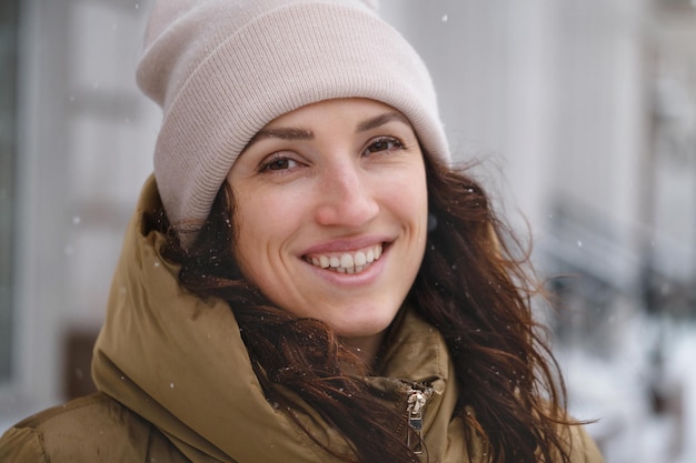 Mulher feliz pegando flocos de neve na cidade no inverno