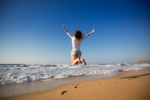 Mulher feliz pulando na praia