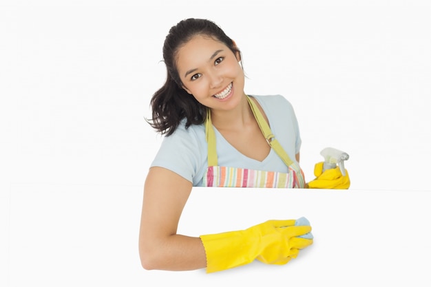 Mulher feliz que limpa a superfície branca