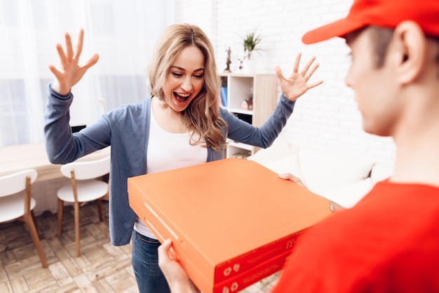 Mulher feliz que olha a caixa e o correio da pizza.