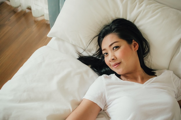 Mulher feliz relaxar na cama de manhã.