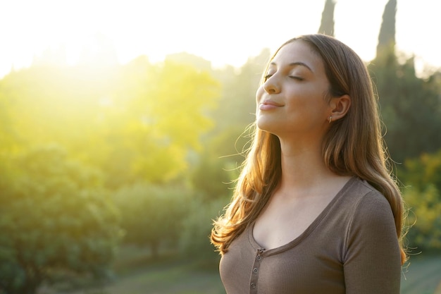 Mulher feliz respirando ar fresco contra um fundo natural. Copie o espaço.