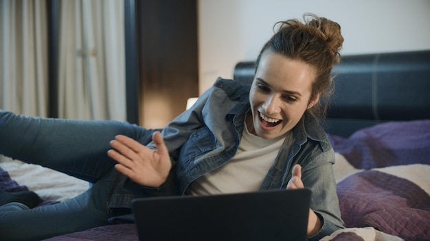 Foto mulher feliz rindo com o laptop em casa pessoa animada batendo palmas