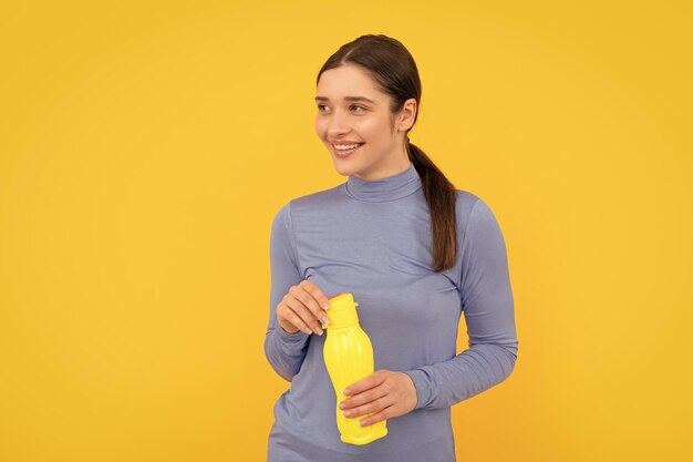 Mulher feliz segura água mineral sente sede, jovem com garrafa de plástico esportiva