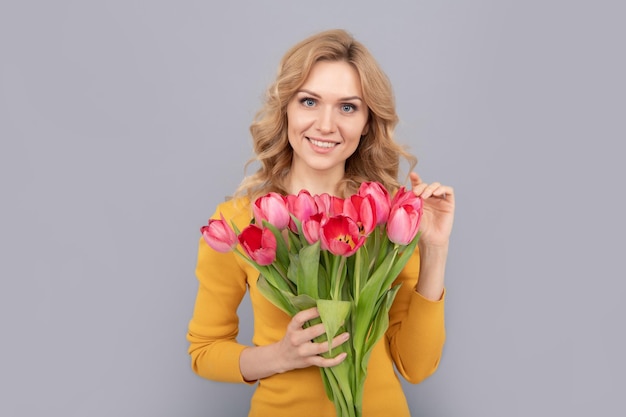 Mulher feliz segura flores para férias de primavera em fundo cinza