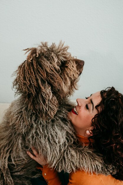 Mulher feliz segurando cão contra a parede em casa