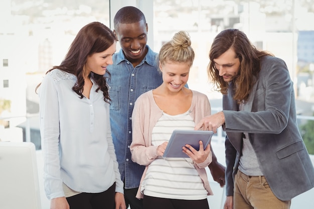 Mulher feliz segurando comprimido digital e discutindo com colegas de trabalho