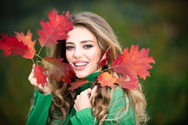 Mulher feliz segurando folhas de outono no rosto no outono retrato de natureza de jovem mulher com a folha de bordo de outono