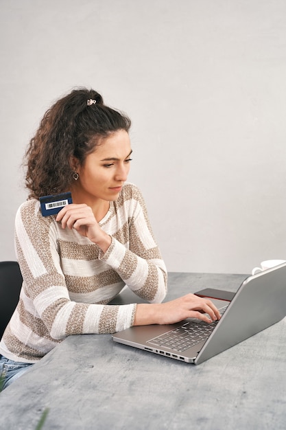 Foto mulher feliz segurando um cartão de crédito e usando o laptop para fazer compras online