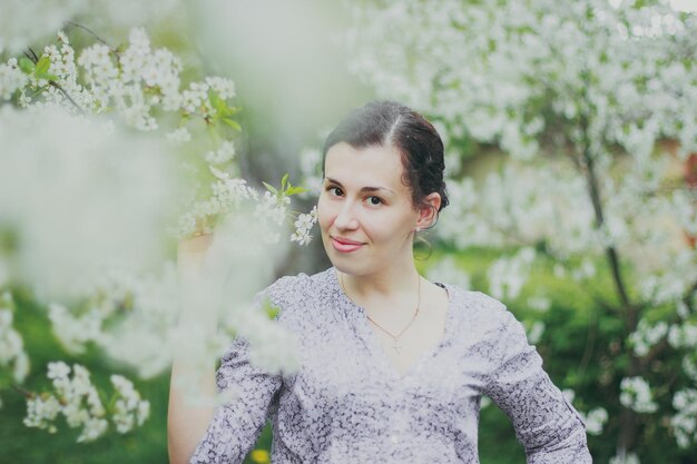 Mulher feliz segurando um galho de flor no jardim de cereja de primavera