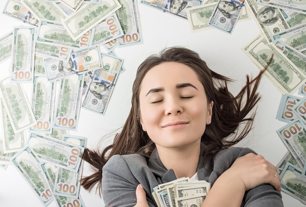 mulher feliz segurando uma pilha de notas de dólar