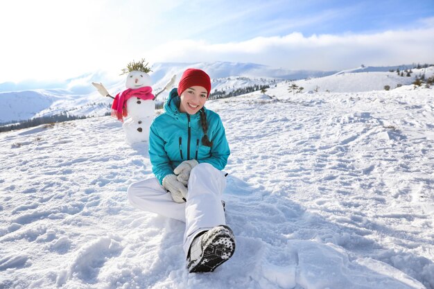 Mulher feliz sentada na colina nevada no resort. Férias de inverno