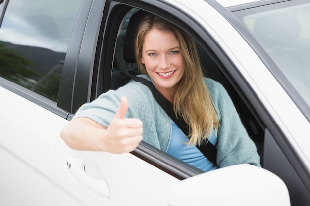 Mulher feliz sentada no assento do motorista polegar para cima