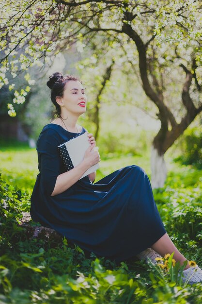 Mulher feliz sentada no jardim de cerejas da primavera