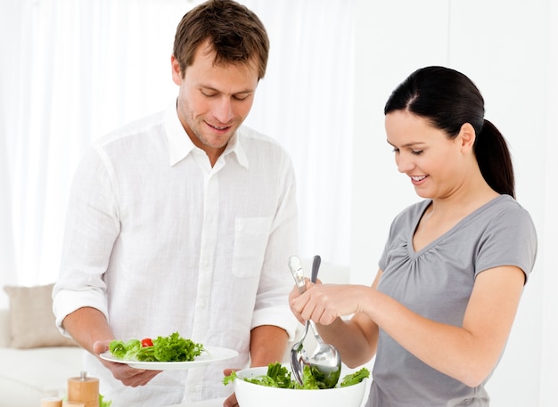 Mulher feliz servindo salada para o namorado para o almoço