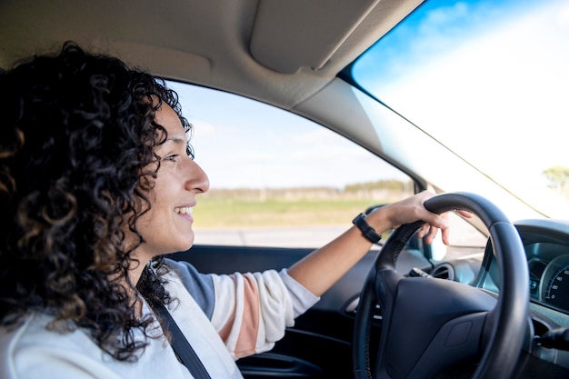 Mulher feliz sorrindo enquanto dirige um carro na estrada