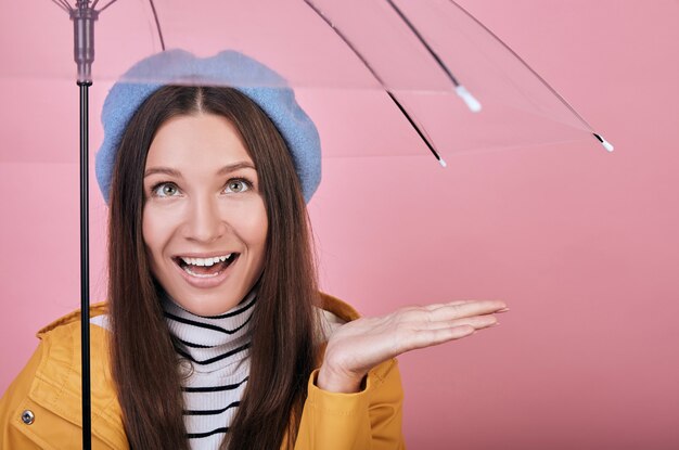 Mulher feliz surpresa na boina azul suave e blusa listrada com guarda-chuva na mão