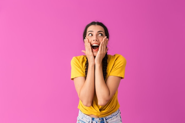 mulher feliz surpresa sorrindo e tocando seu rosto com as mãos isoladas na parede rosa