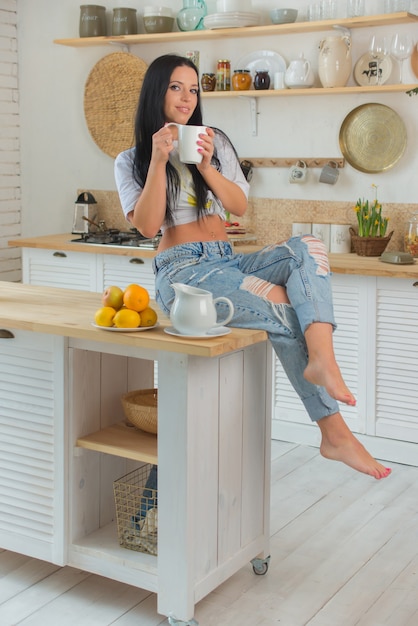 Mulher feliz tomando chá na cozinha de casa