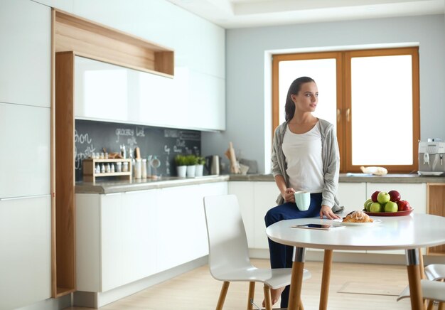 Mulher feliz tomando chá na cozinha de casa