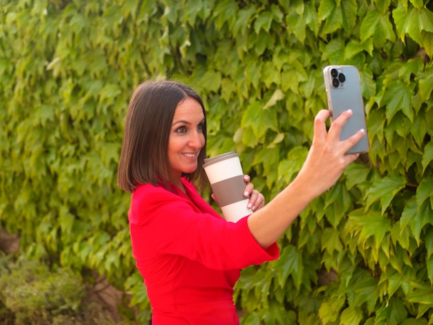 Mulher feliz tomando selfie com copo perto de cerca de uvas