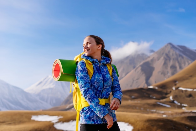 Mulher feliz turista no fundo de altas montanhas em um dia ensolarado