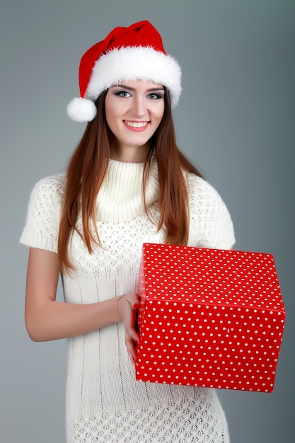 Mulher feliz usando chapéu de Papai Noel segurando a caixa de presente Feche o retrato com ombros